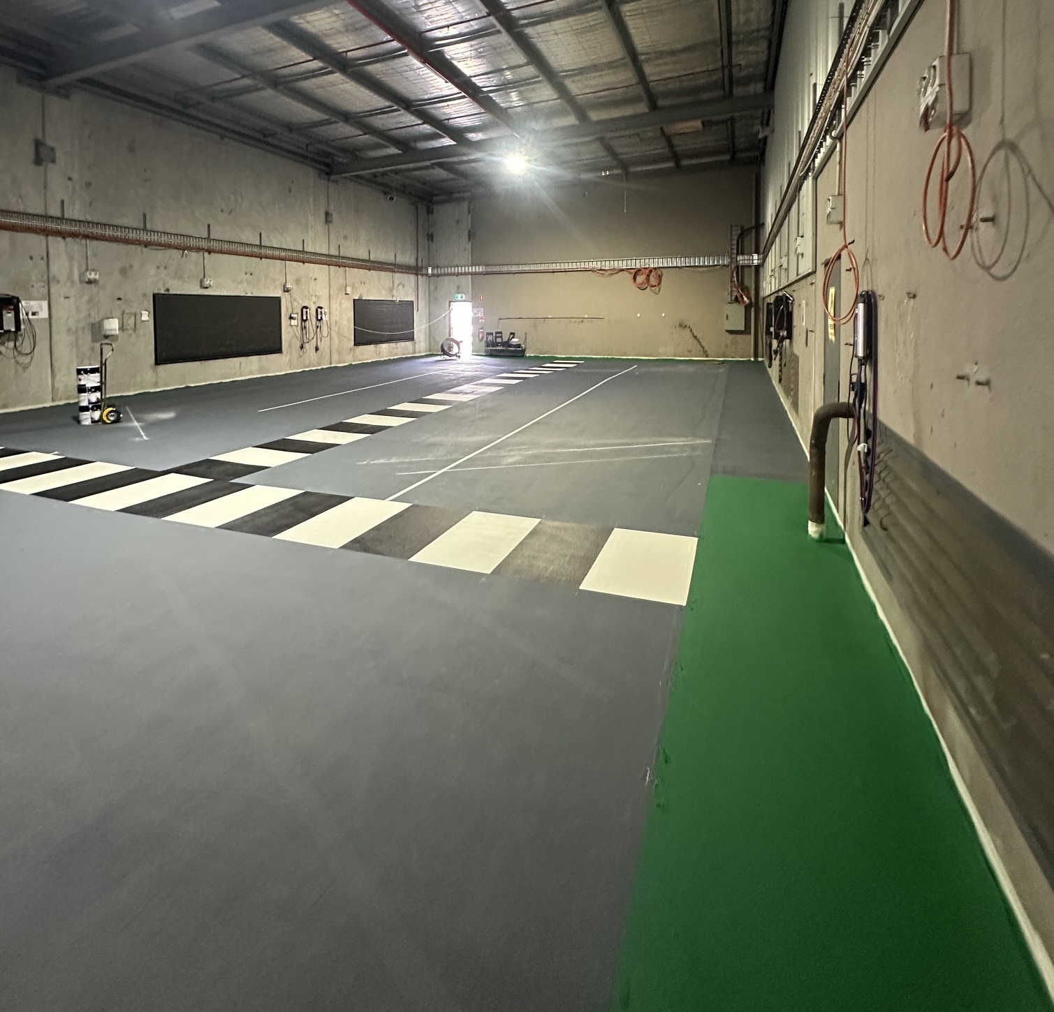 Black and white pedestrian crossing with green safety zone in warehouse