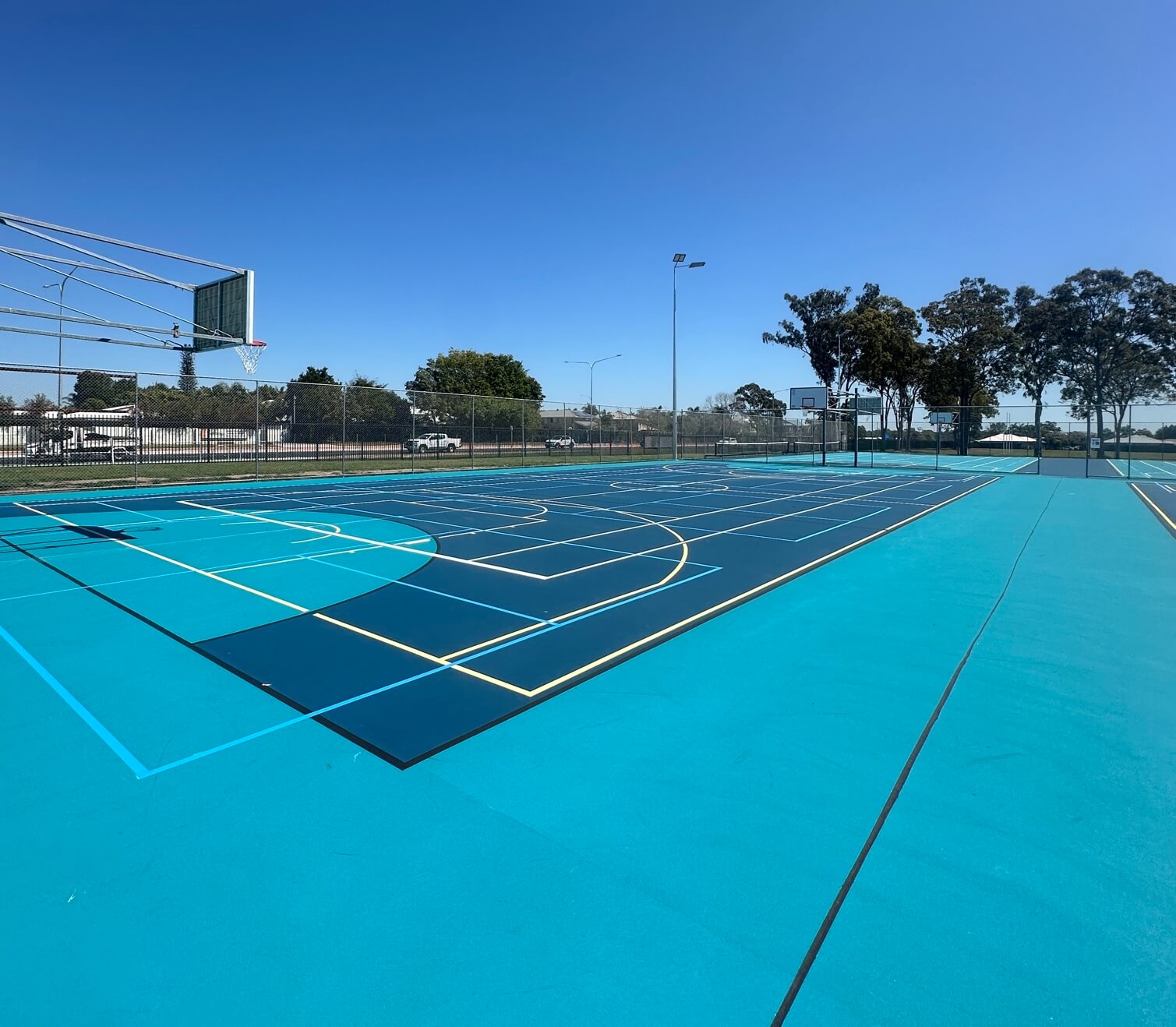 Teal and navy outdoor sports court with multi-sport basketball line marking
