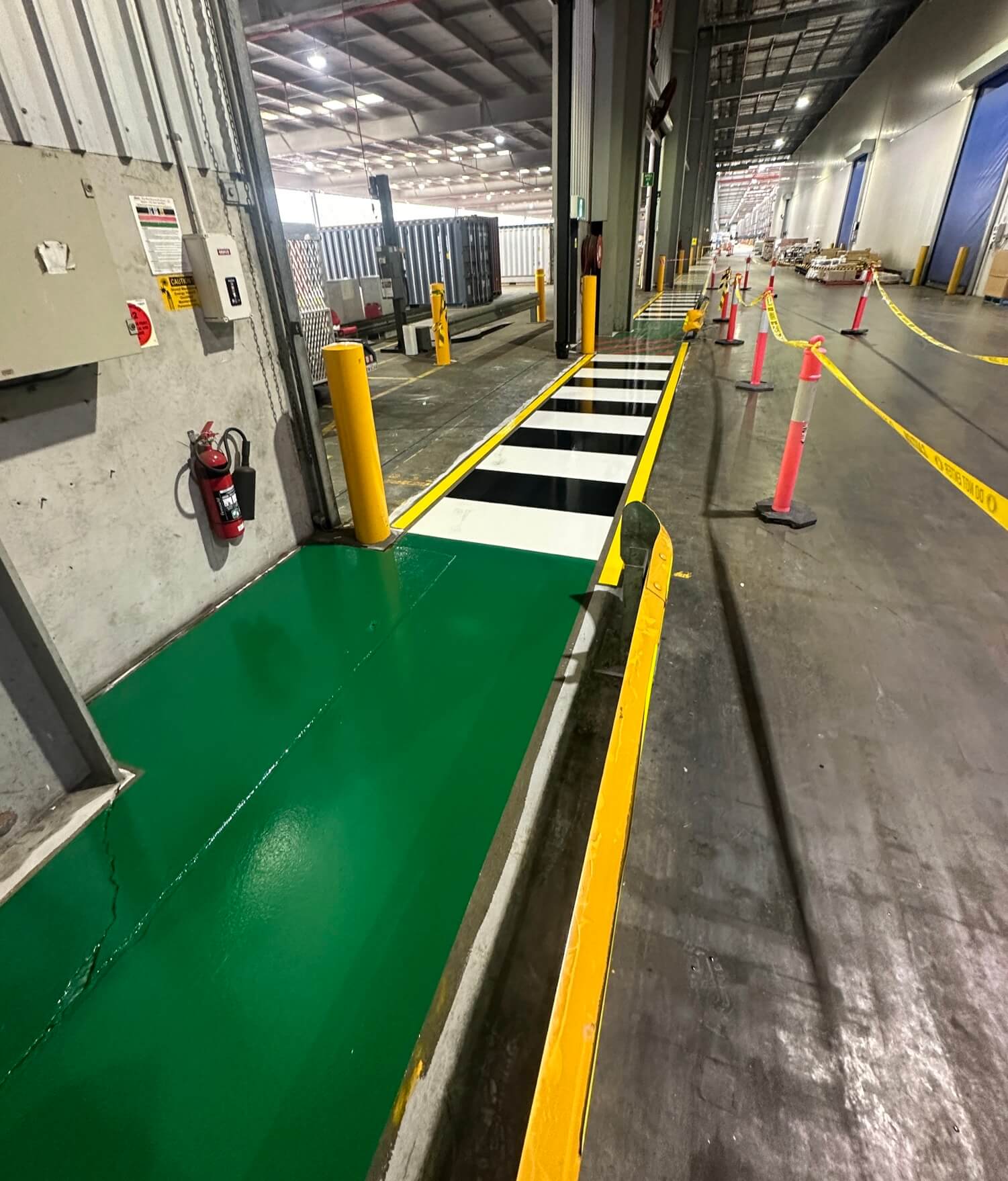 Warehouse loading dock green safety zone with black and white pedestrian crossing