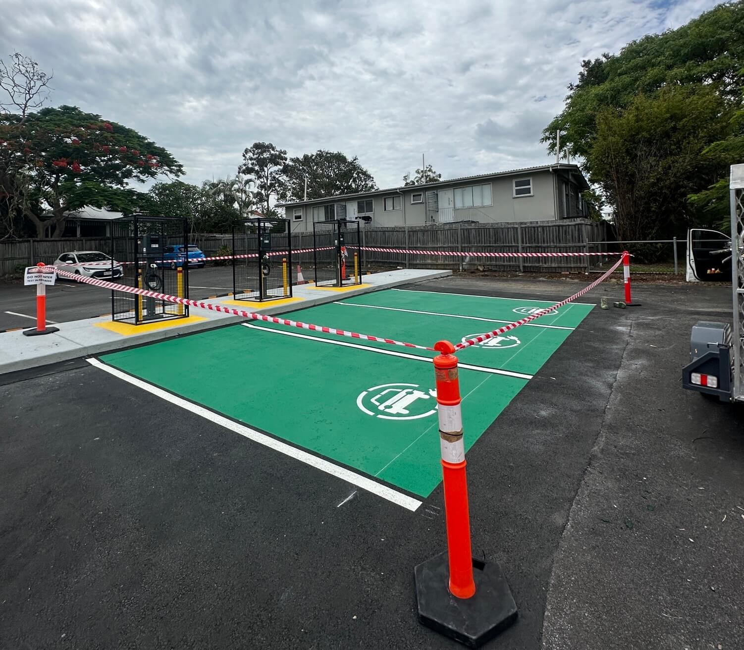 Newly marked green EV charging bay beside charger units in an outdoor car park