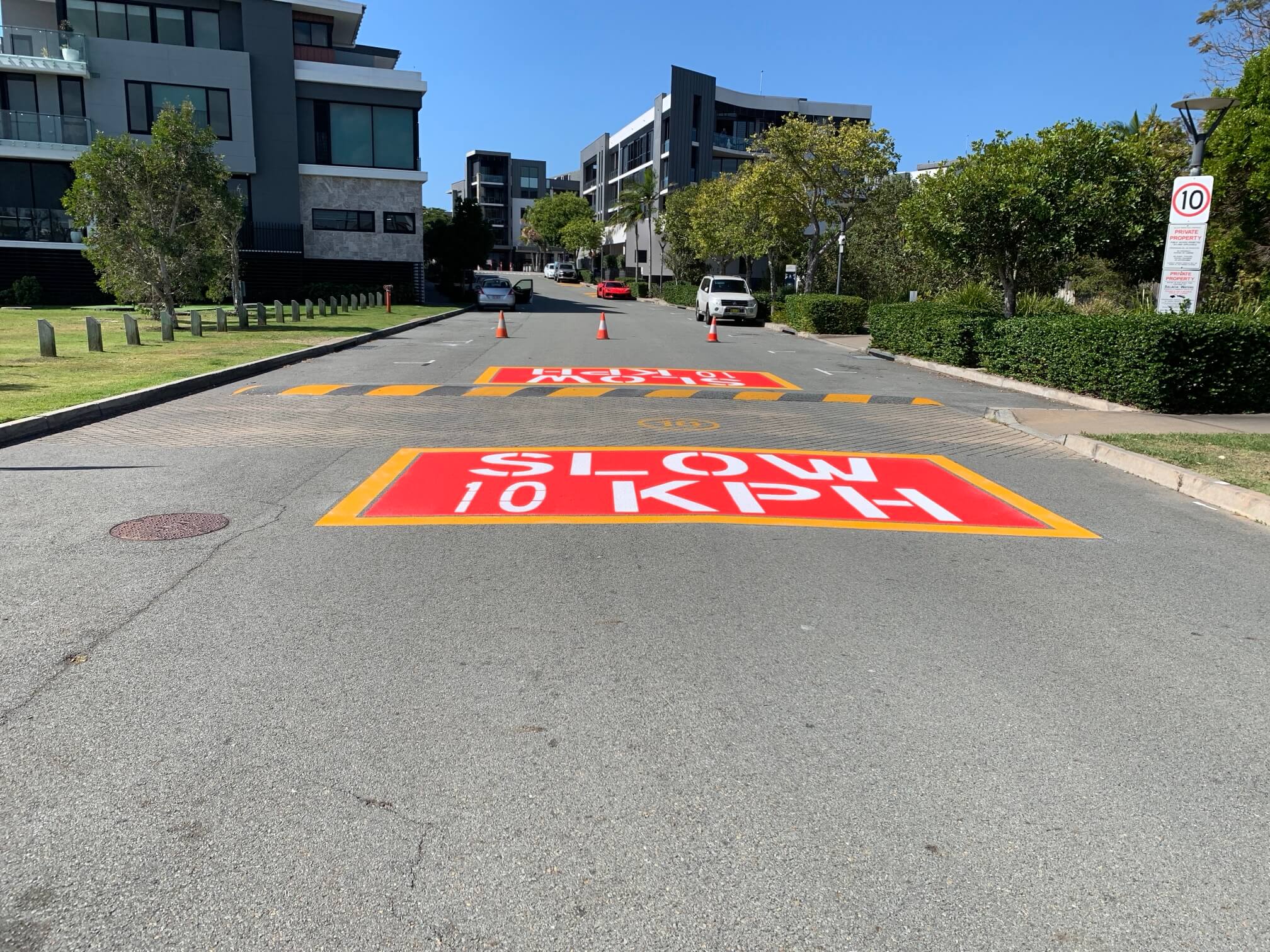 Paradise Point, Gold Coast residential estate road with red and yellow SLOW 10 KPH stencilled line marking and hazard striped raised speed table