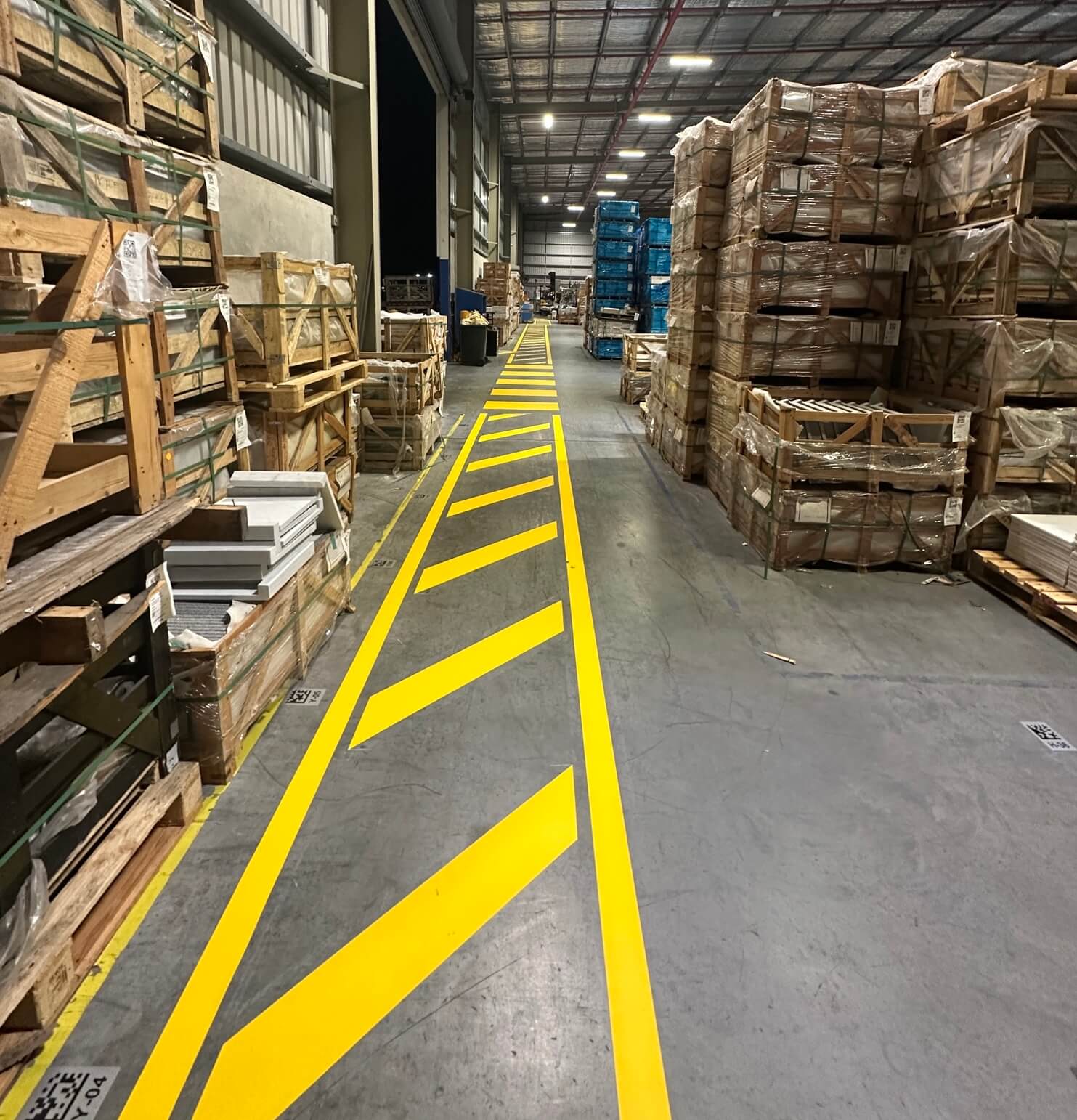 Warehouse yellow hazard pedestrian walkway line marking between pallet racks
