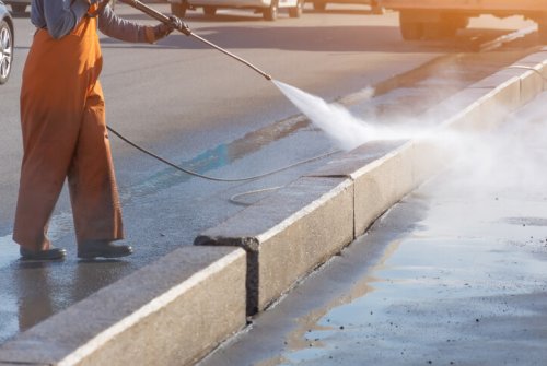 Worker pressure cleaning kerb and gutter with high-pressure water