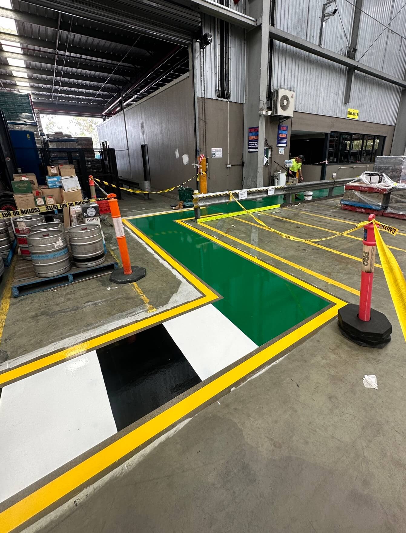 Warehouse green safety zone with yellow borders and pedestrian crossing