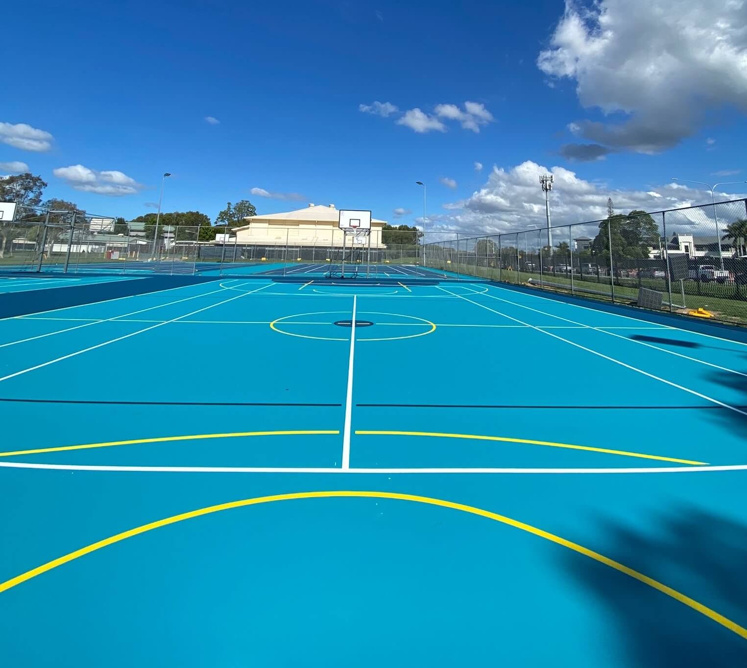 Blue outdoor sports court with multi-sport basketball and netball line marking