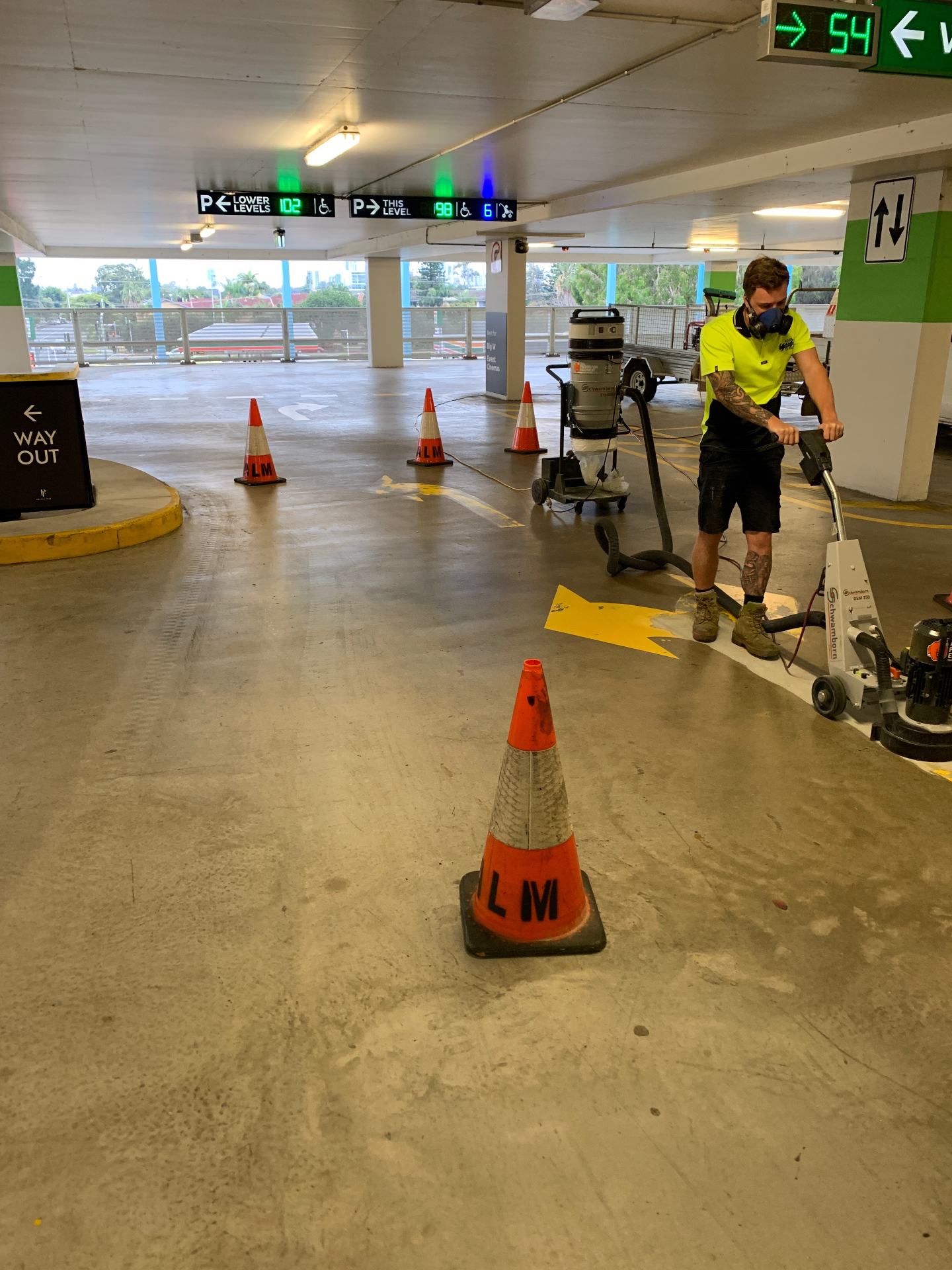 Operator grinding out an old yellow directional arrow in a car park