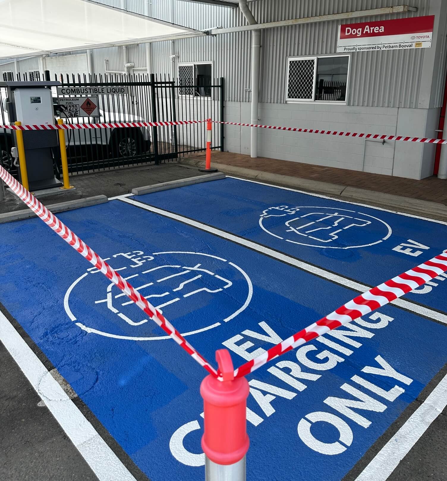 Blue EV charging only bays with white plug symbol stencils at a dealership