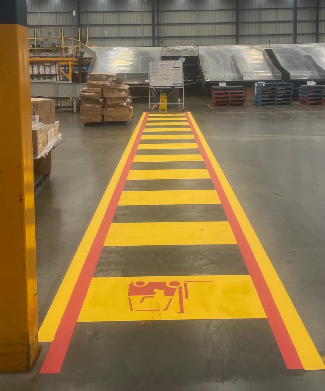 Warehouse pedestrian crossing marked in yellow and red with forklift symbol