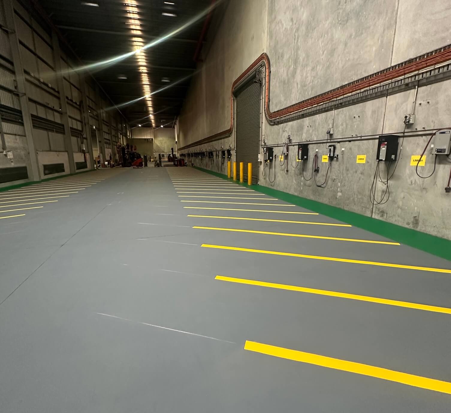 Warehouse floor with yellow line marked parking bays beside a roller door