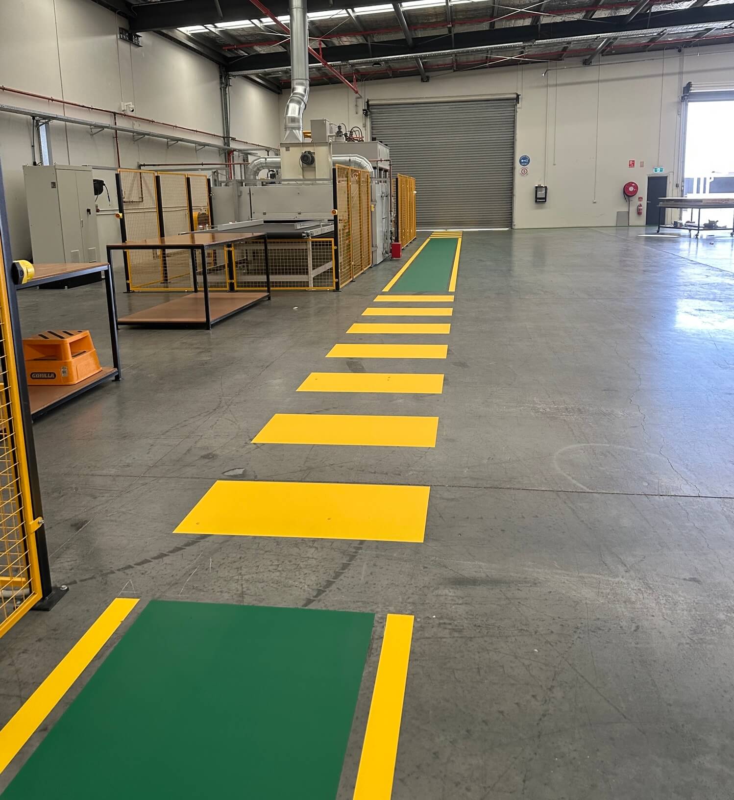 Factory yellow pedestrian walkway leading to a green safety zone