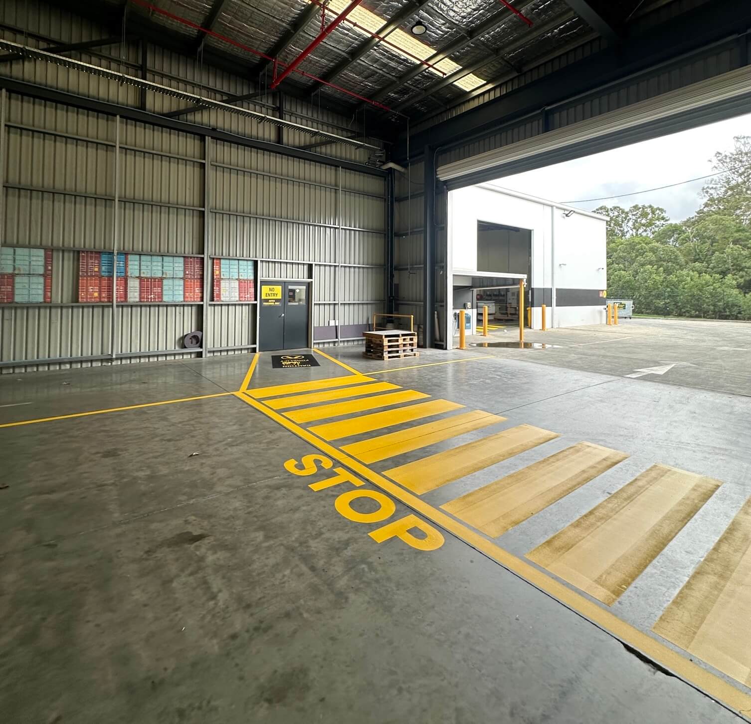 Industrial warehouse entrance with yellow STOP marking and pedestrian crossing