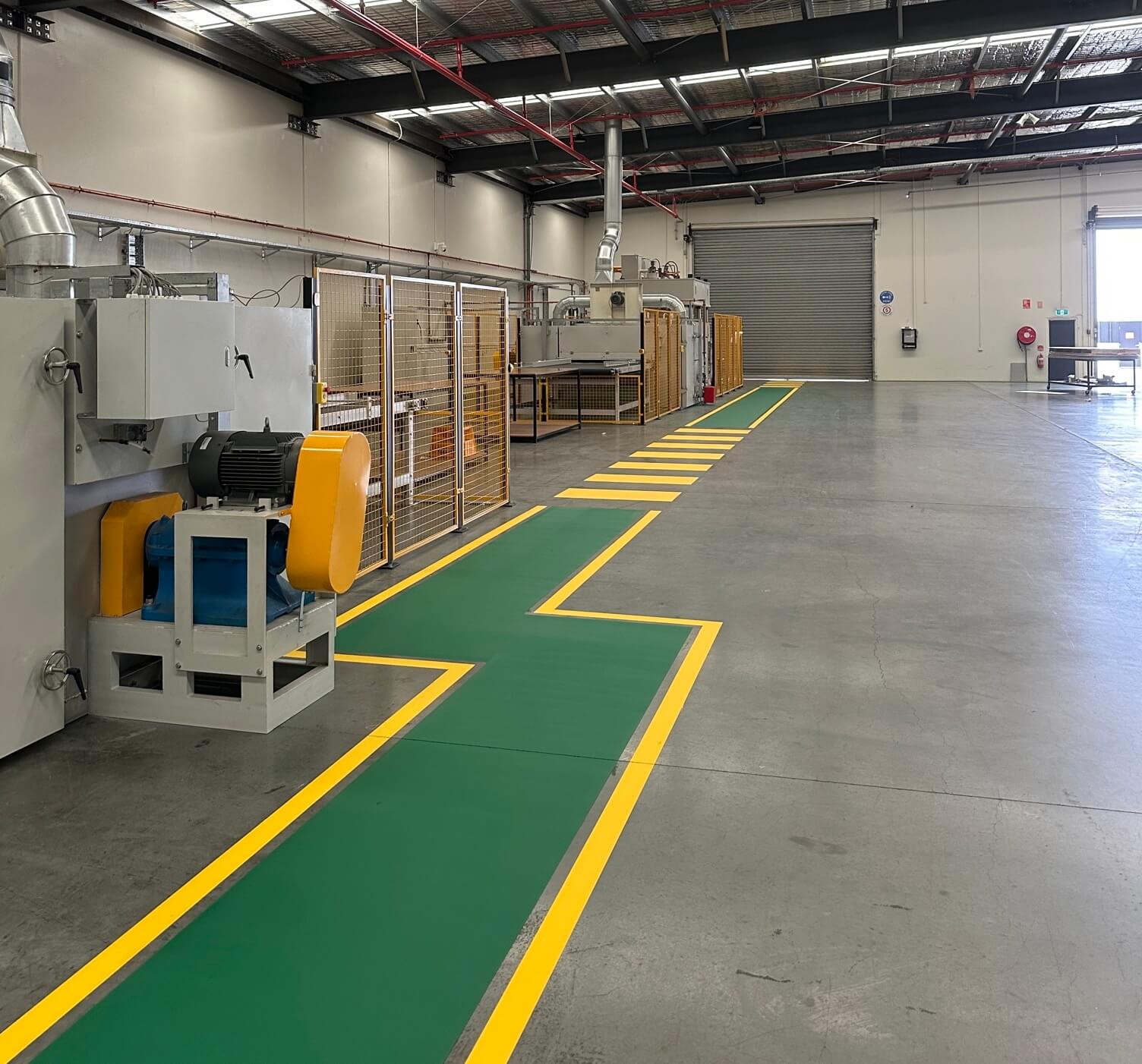 Factory green pedestrian walkway with yellow zigzag safety borders