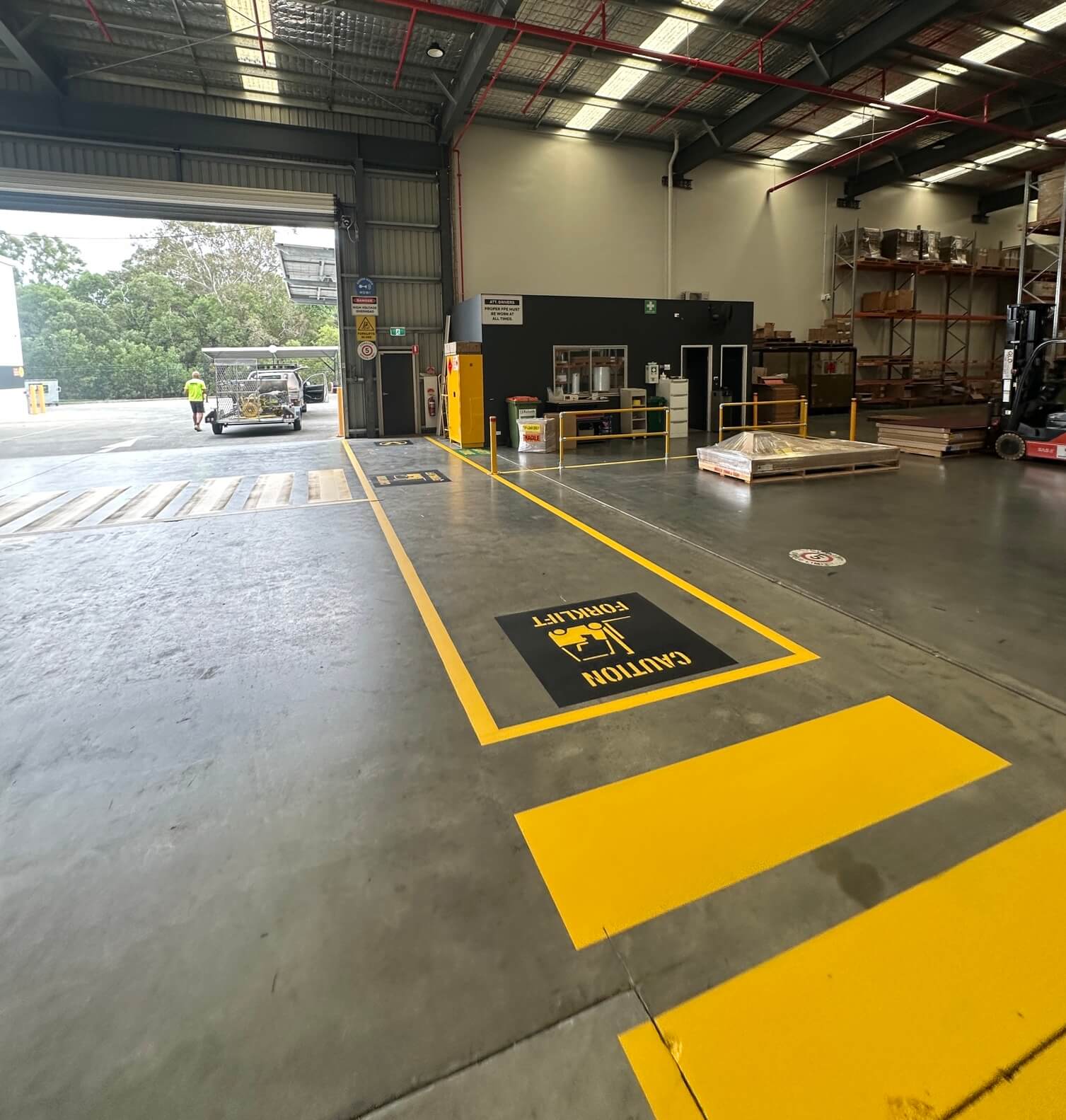 Warehouse yellow forklift caution zone marking with stencilled safety symbol
