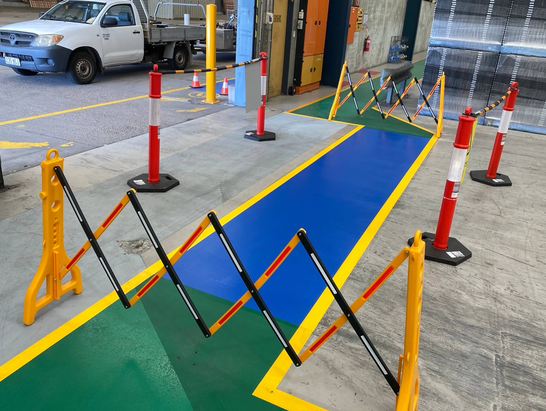 Warehouse blue pedestrian walkway with yellow borders and safety bollards