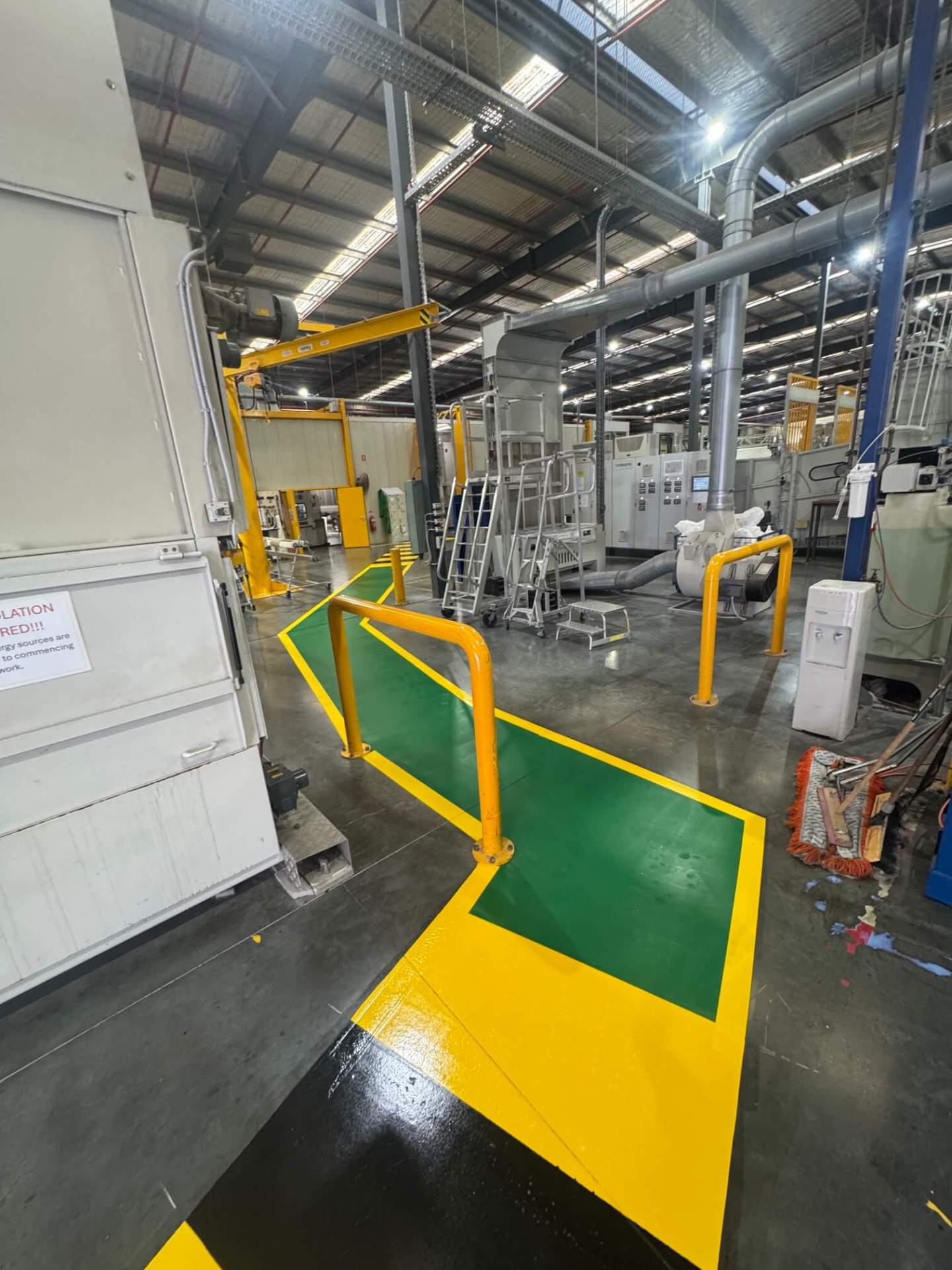 Factory green and yellow pedestrian safety walkway between machinery