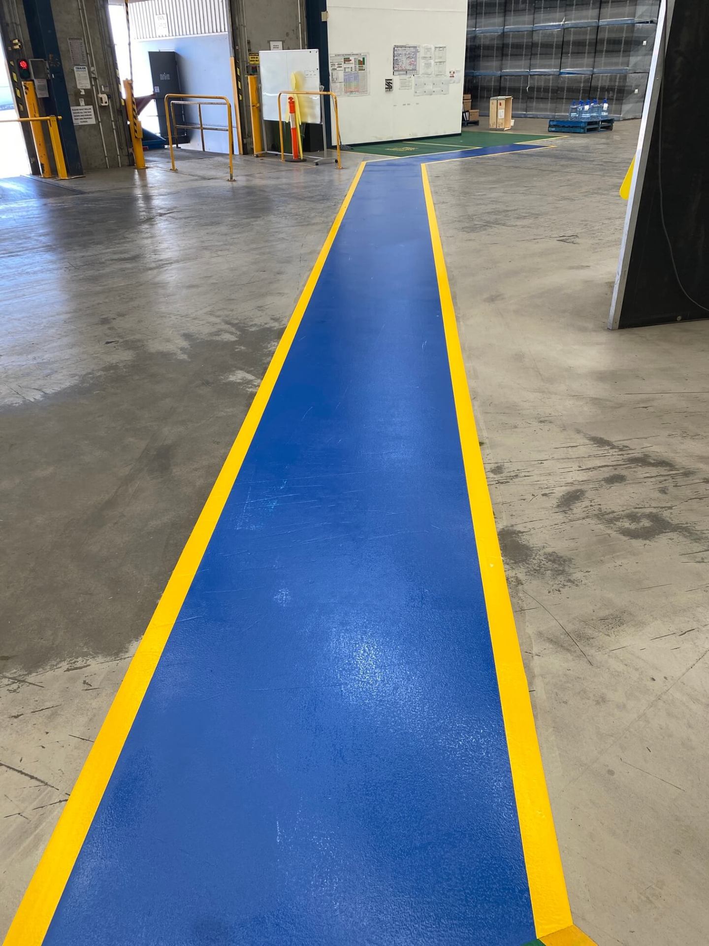 Long warehouse blue pedestrian walkway with yellow border line marking